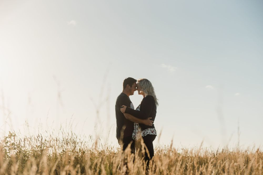 engaged couple cuddling at sunset