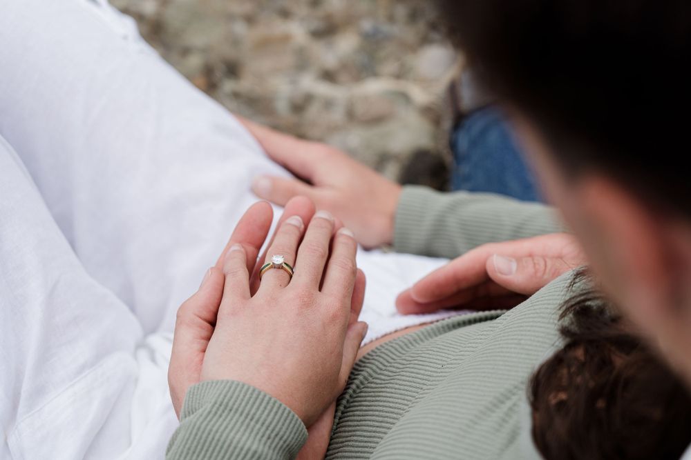 Close up of couple sitting looking down at their hands and engagement ring