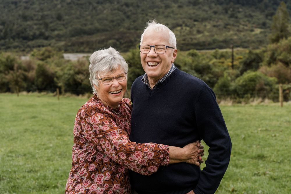 Elderly couple hugging and laughing engaged couple dancing on the road on the family farm at Jacksons on the West coast of New Zealand