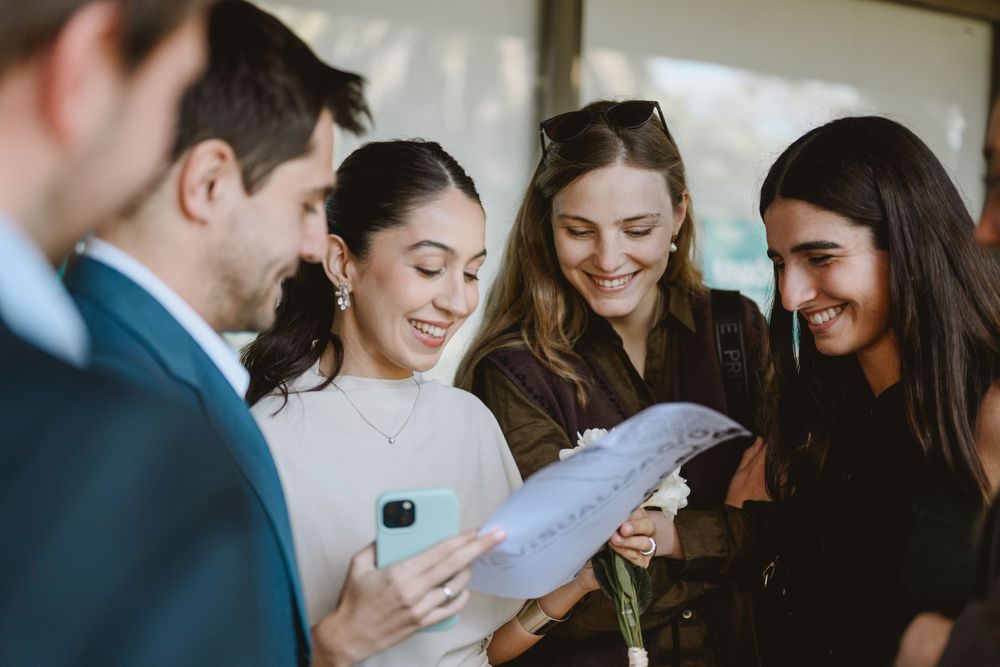 Group of young professionals smiling and reviewing documents together at an outdoor event.