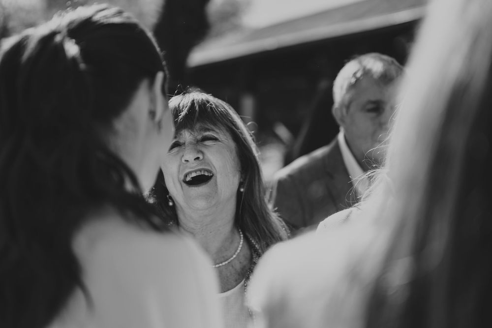 Black and white candid photo of woman laughing joyfully at a social gathering.