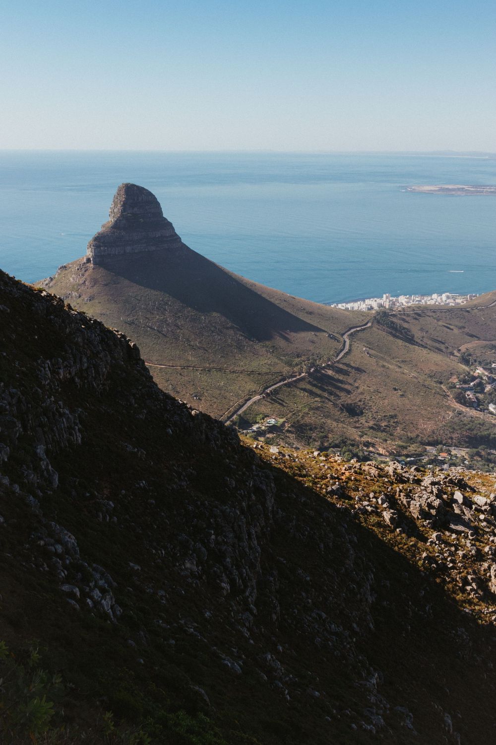 Aerial view of Lions Head mountain peak overlooking Cape Town coastline and blue ocean.