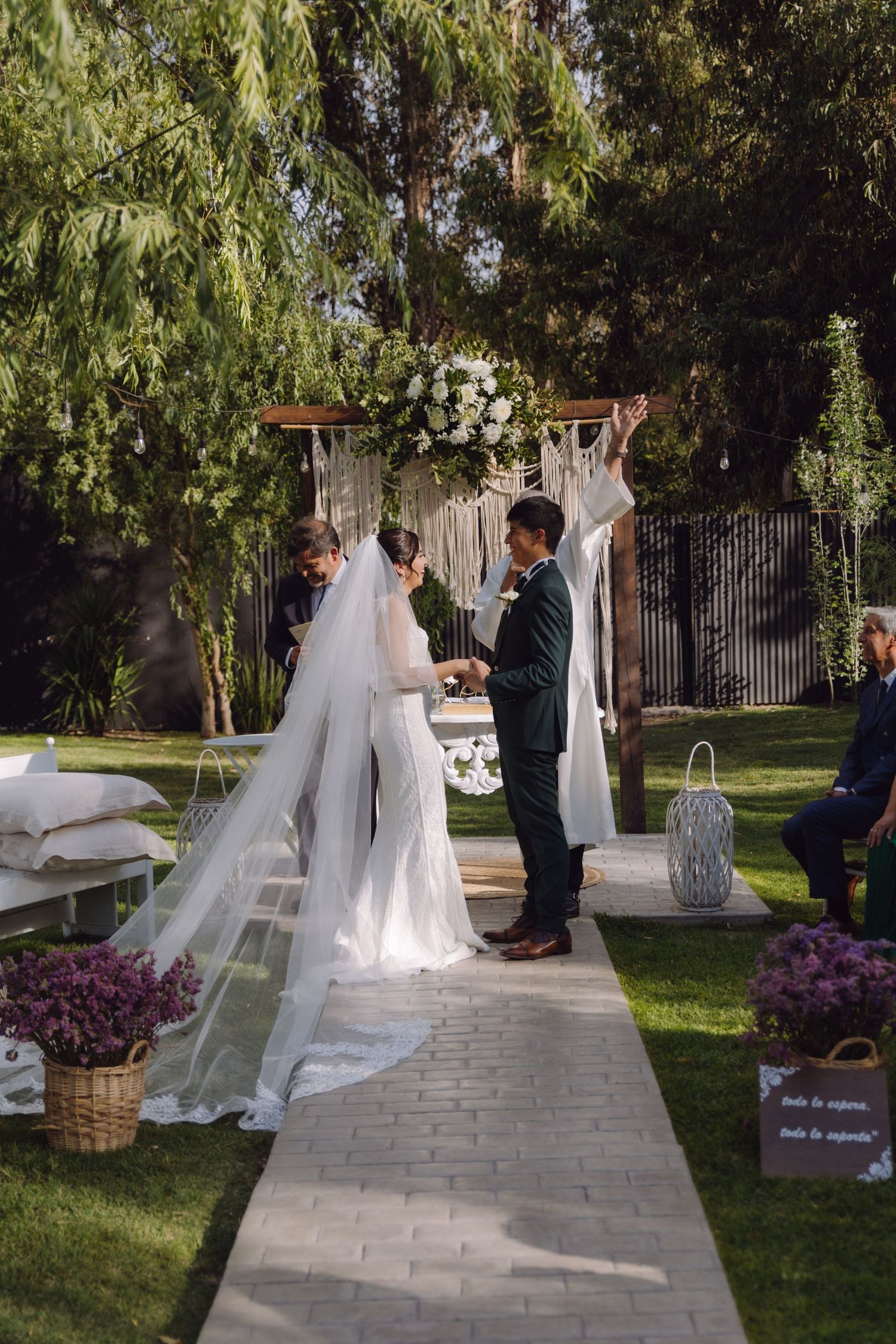 Bride and groom exchange vows under floral arch at elegant outdoor garden wedding ceremony.