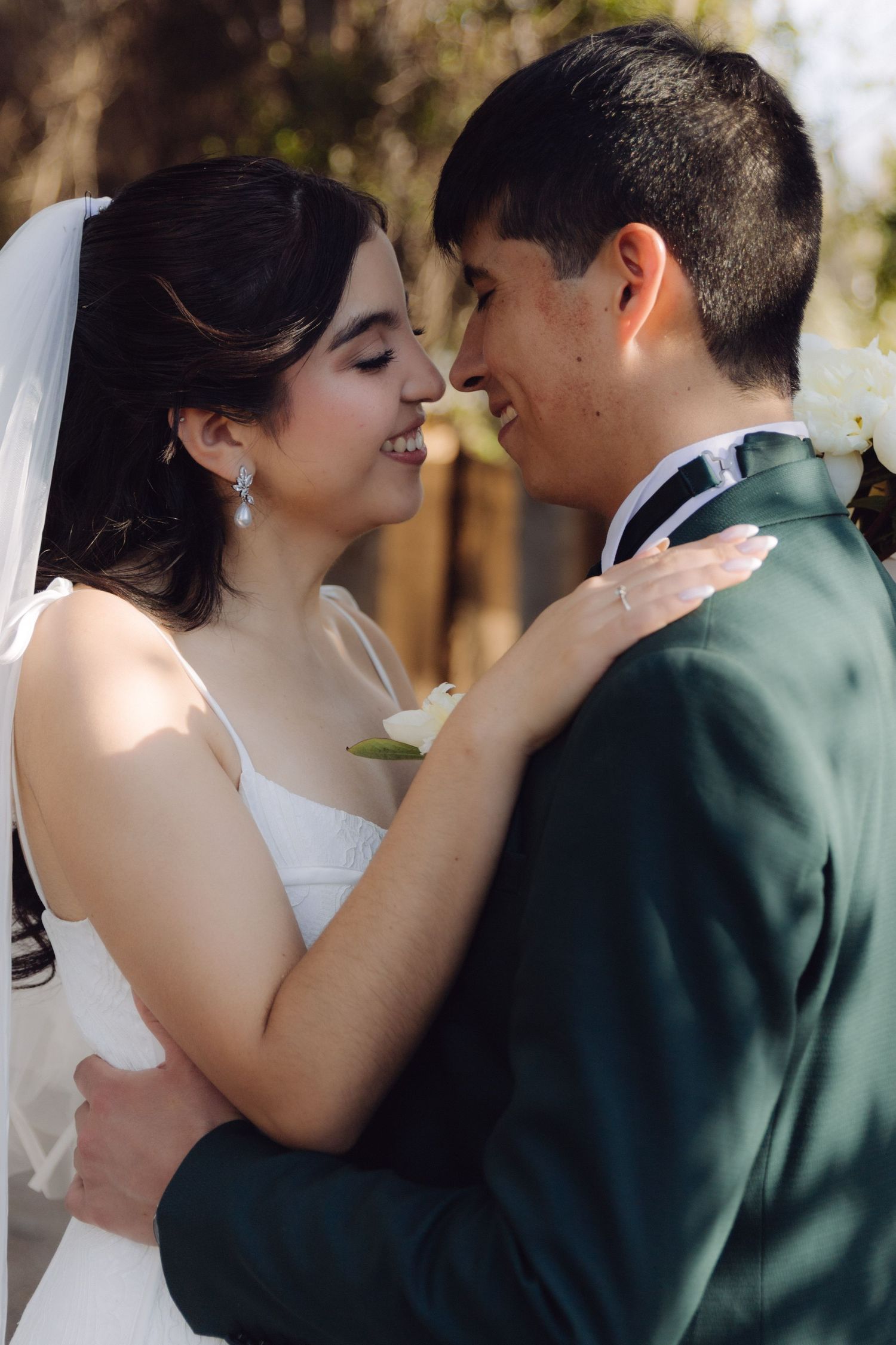 Bride and groom share a romantic close moment, smiling at each other during their outdoor wedding.
