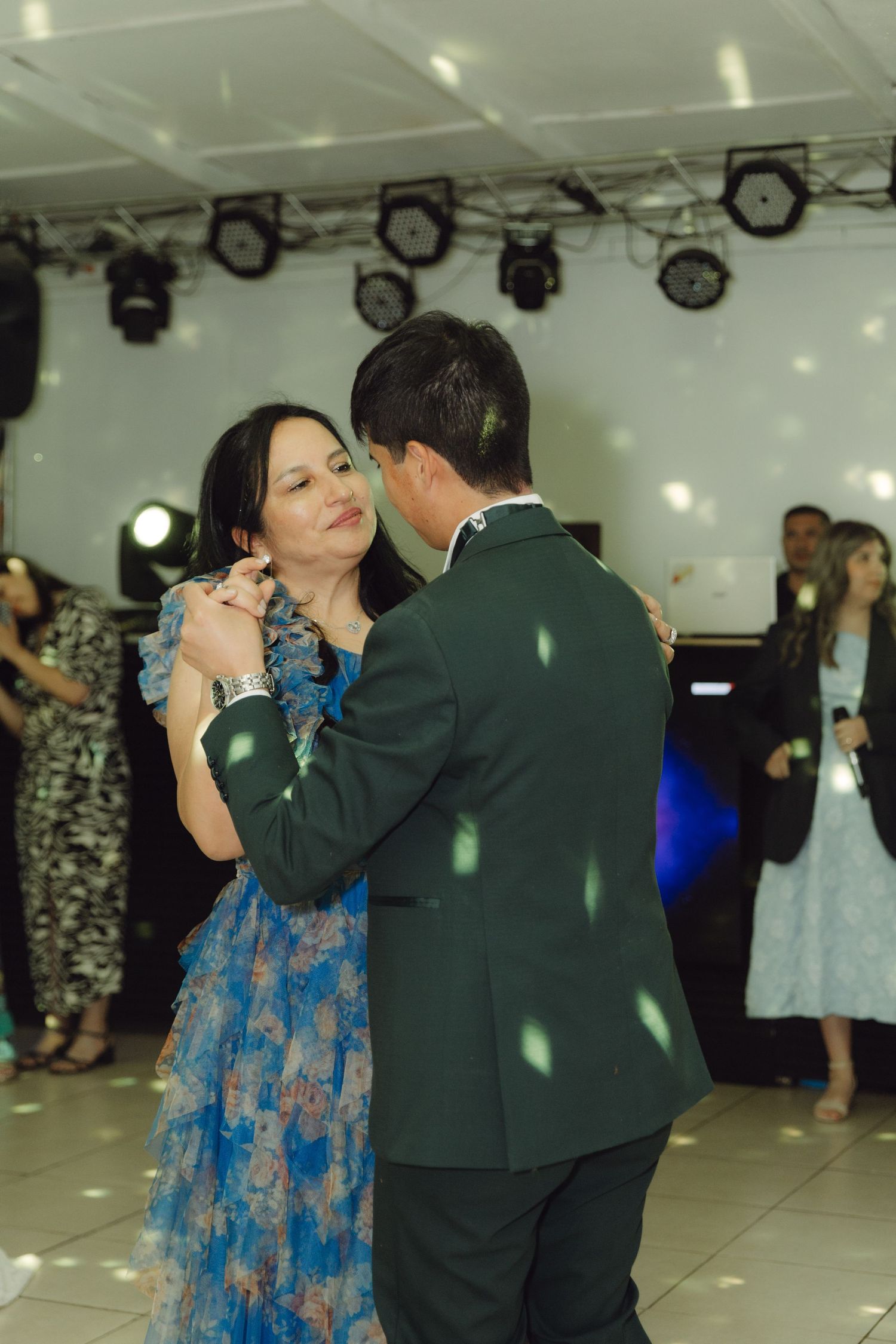Couple sharing a romantic dance together at a wedding reception with guests watching in background.