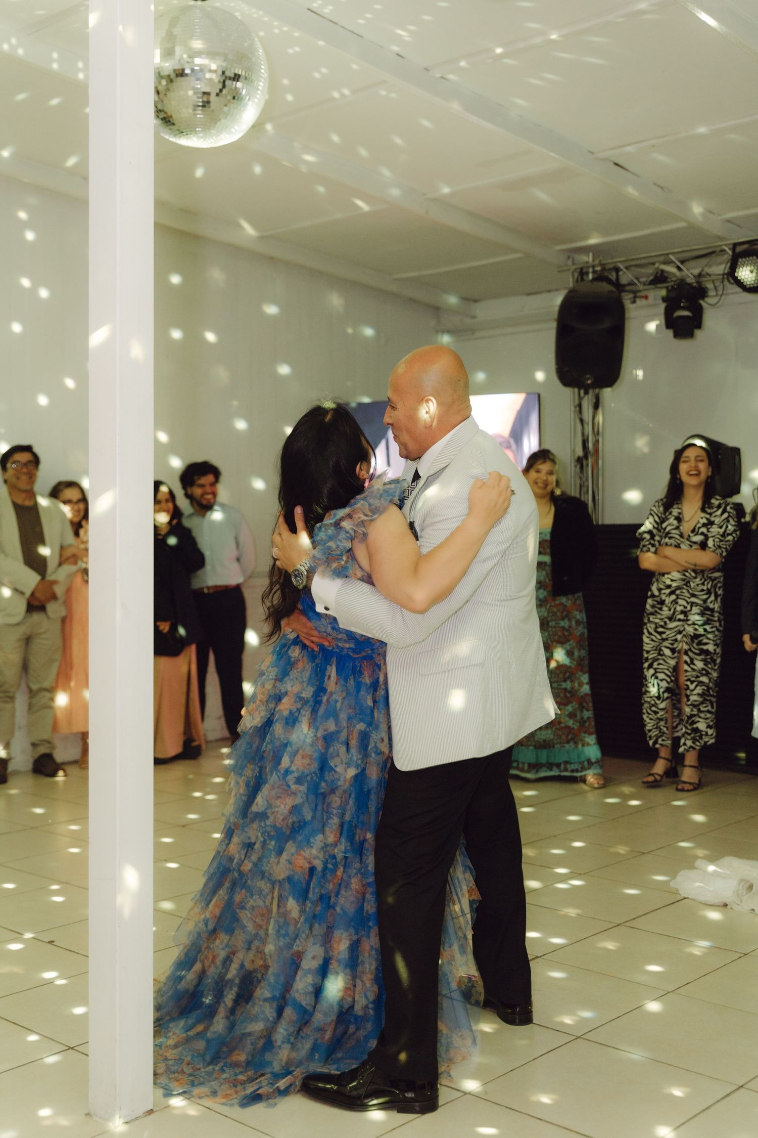 Couple sharing a slow dance on the wedding reception dance floor under a disco ball.