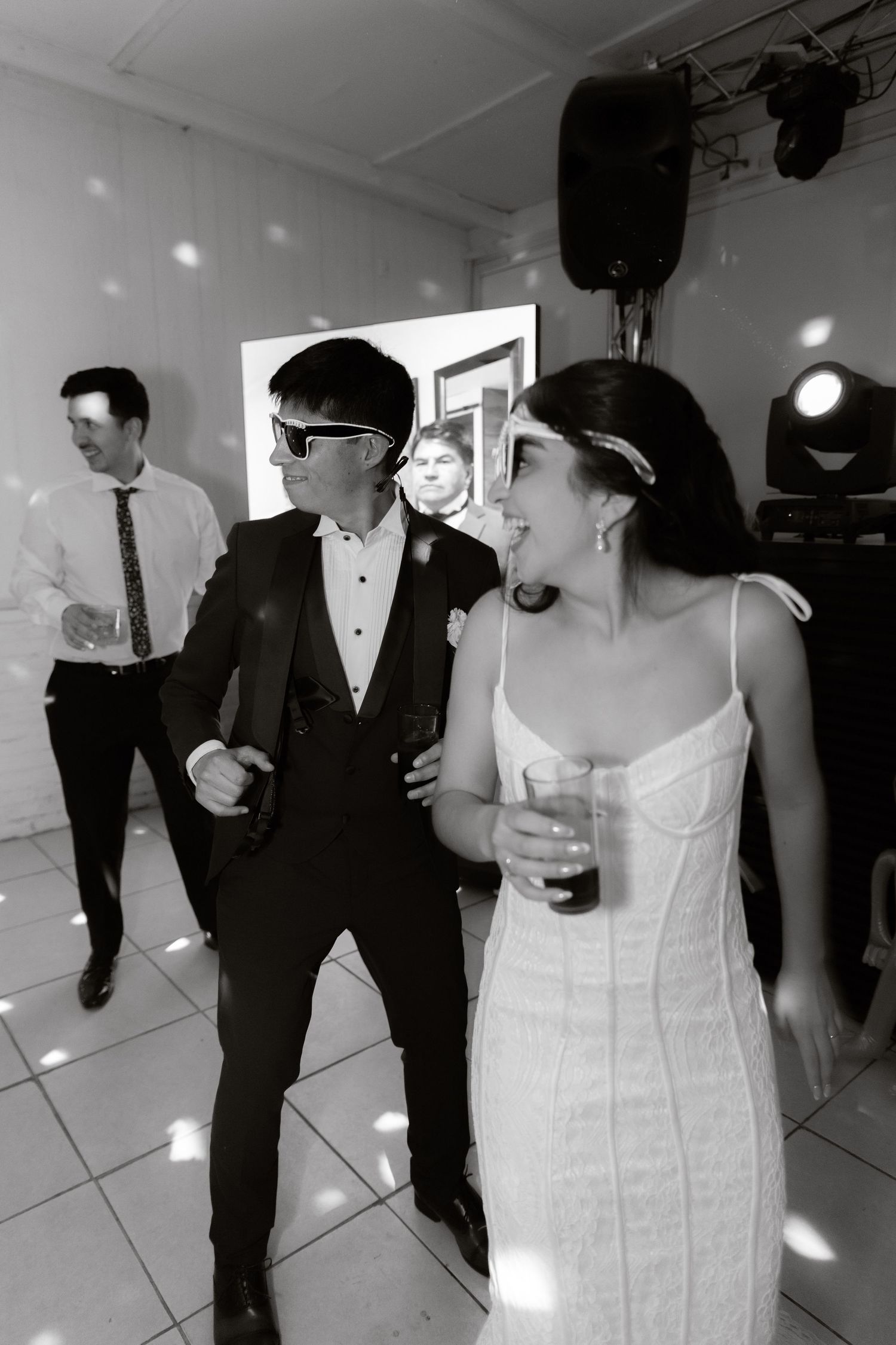 Black and white photo of bride and groom dancing together at wedding reception celebration.