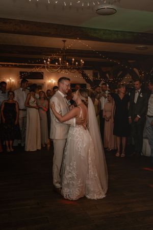 Braut und Bräutigam tanzen ihren ersten Hochzeitstanz in einer rustikalen Scheune, stimmungsvoll beleuchtet von Kerzen und Lichterketten.