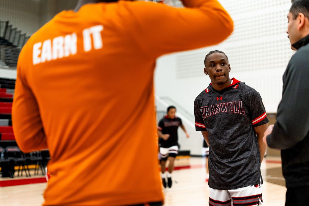 Basketball player in Braswell jersey listens to referee during a captains meeting.