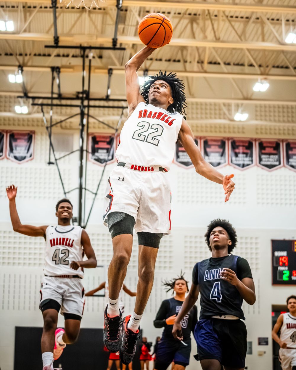 Braswell player number 22 leaps for a powerful dunk during a high school basketball game.
