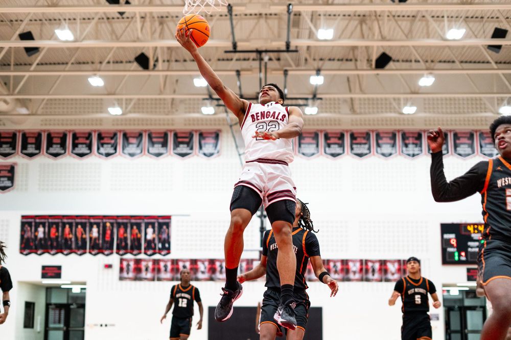 Bengals player drives to the basket for a layup in an intense basketball game.