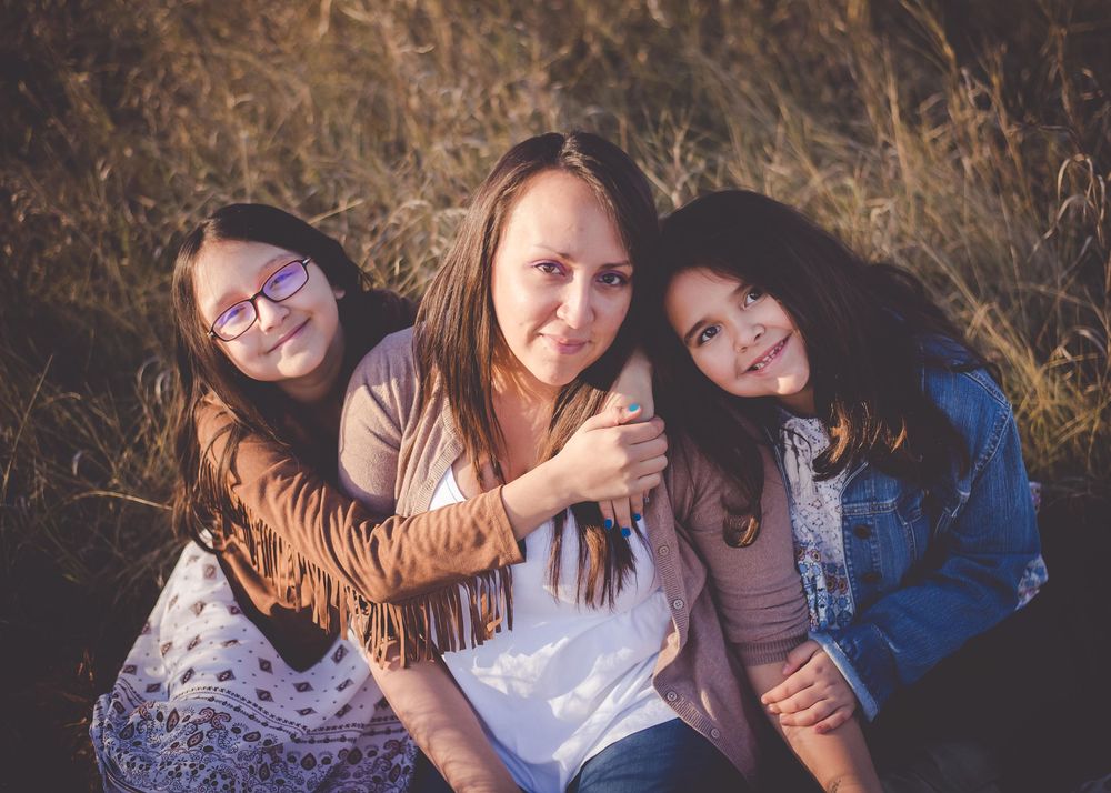Mother embracing her two daughters outdoors during a family photography session