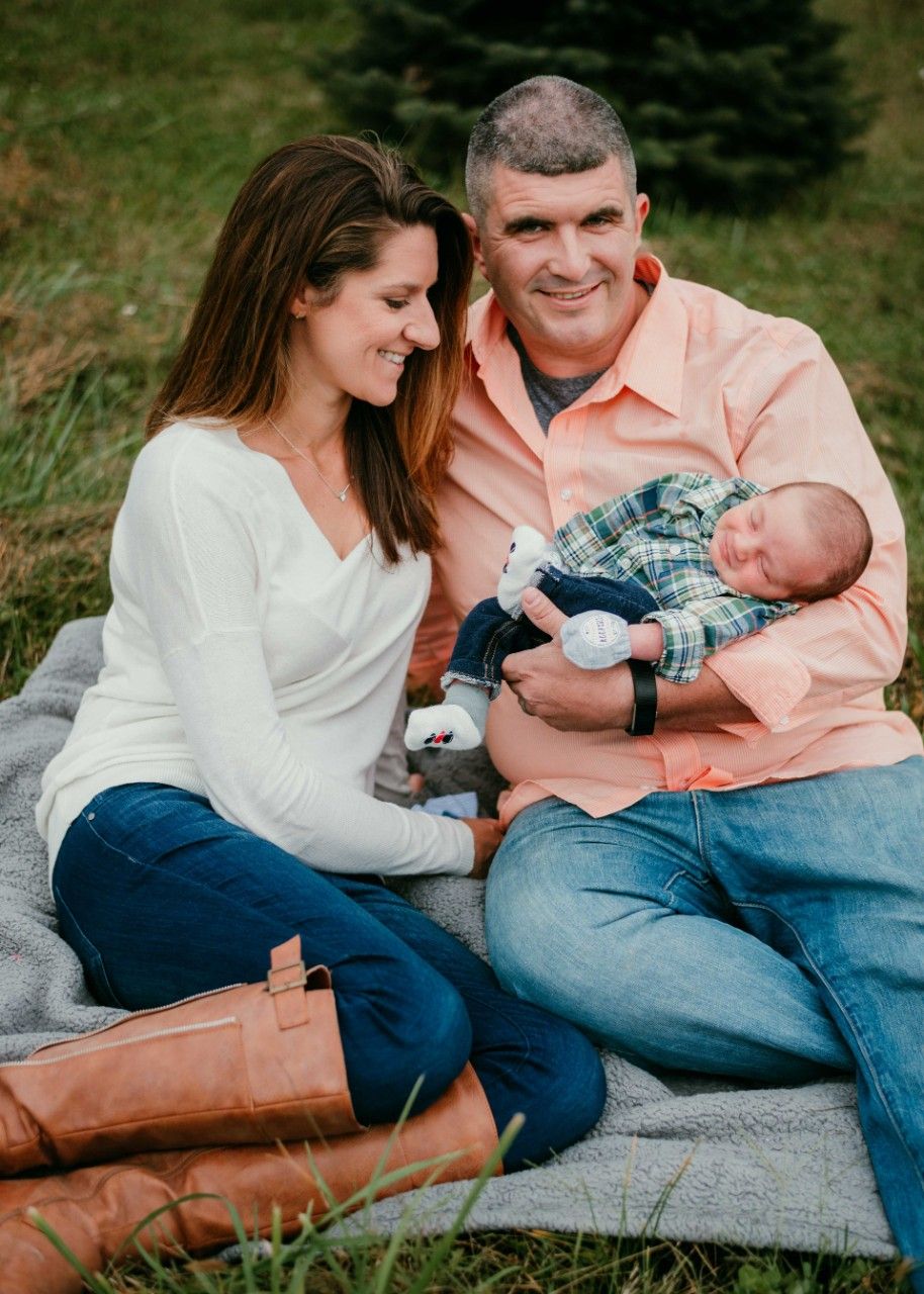 Parents holding their newborn baby together during an outdoor family photography session