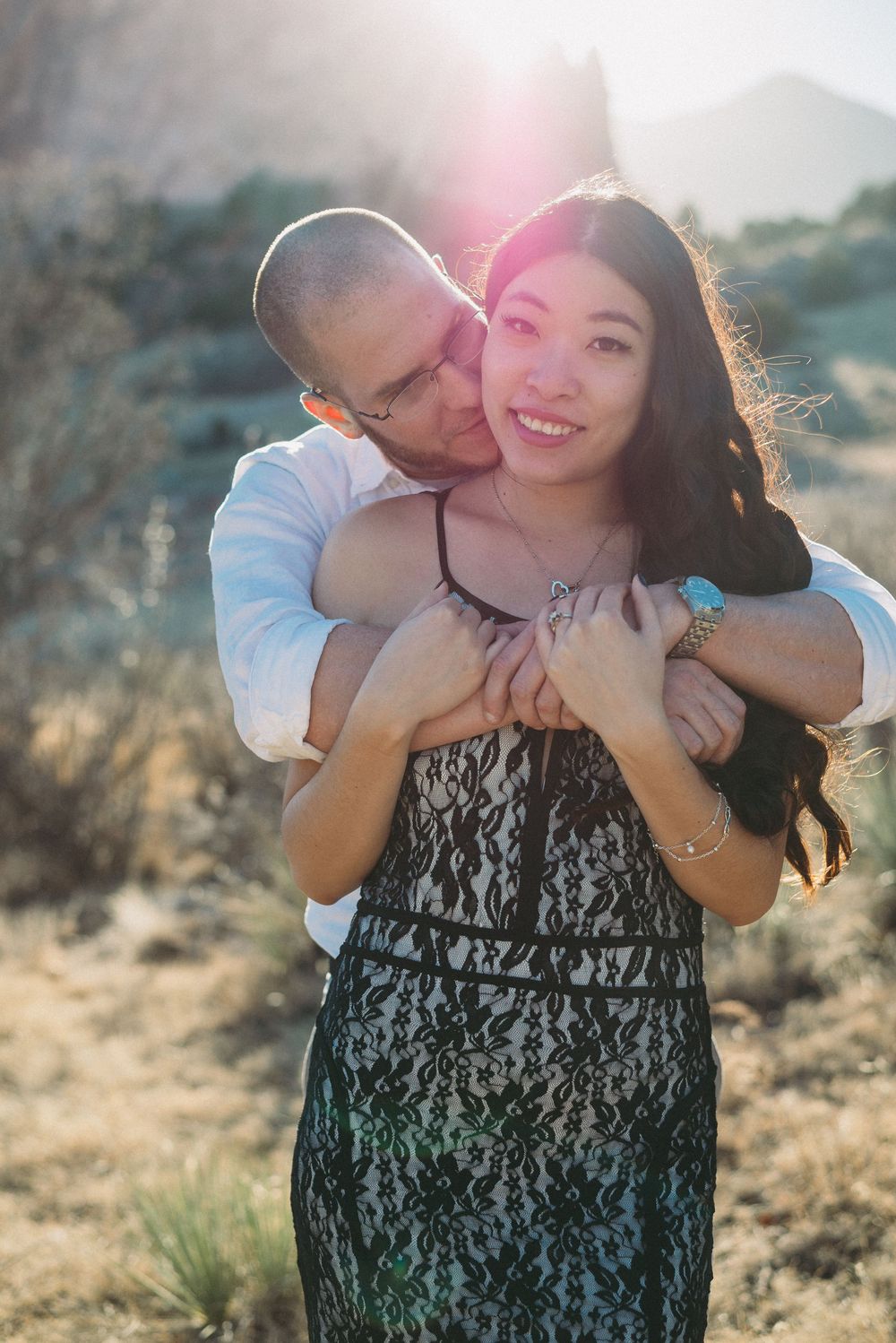 Couple embracing outdoors in warm evening sunlight during an outdoor portrait session
