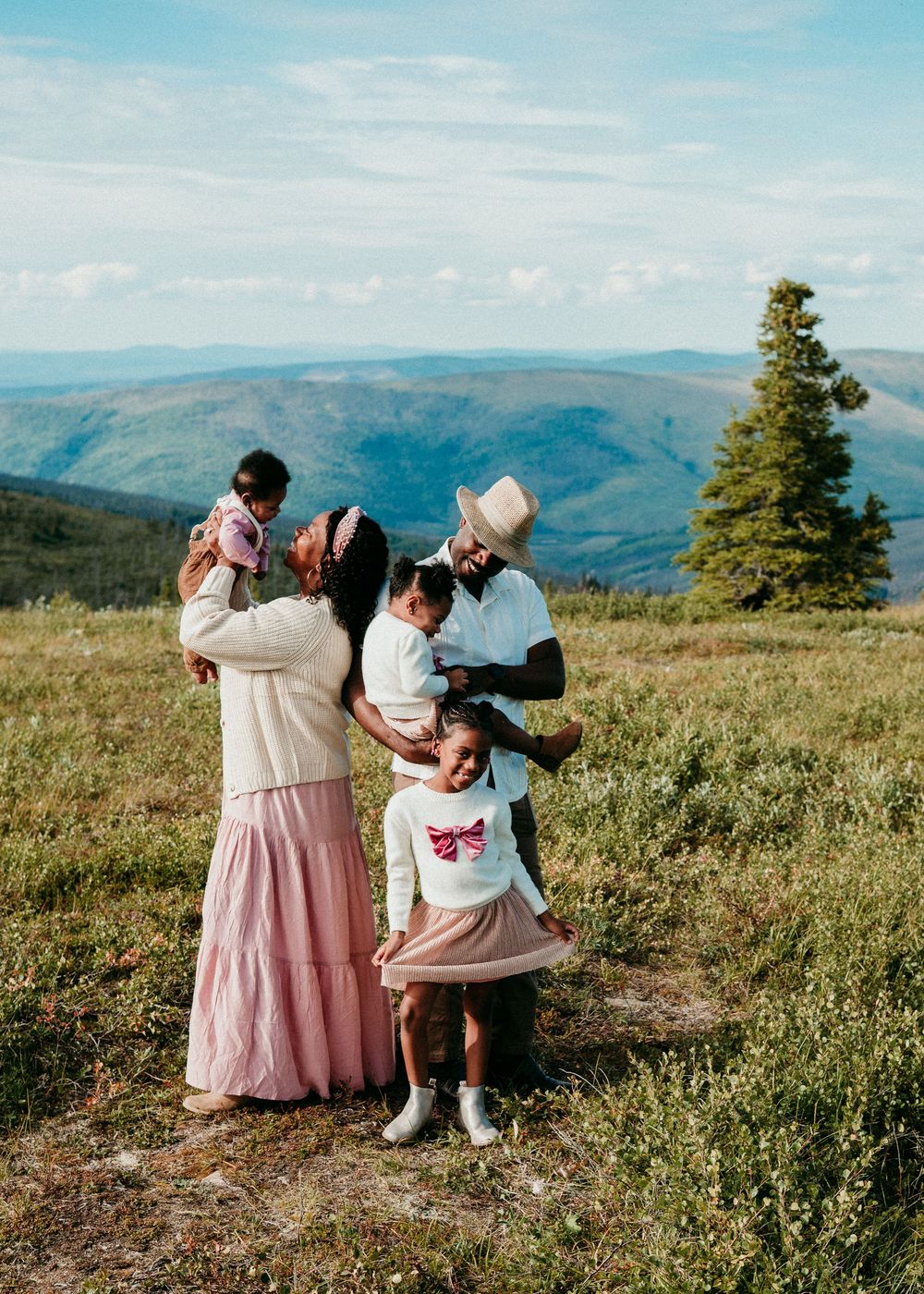Family standing together in a grassy field with mountains in the background during an outdoor family session