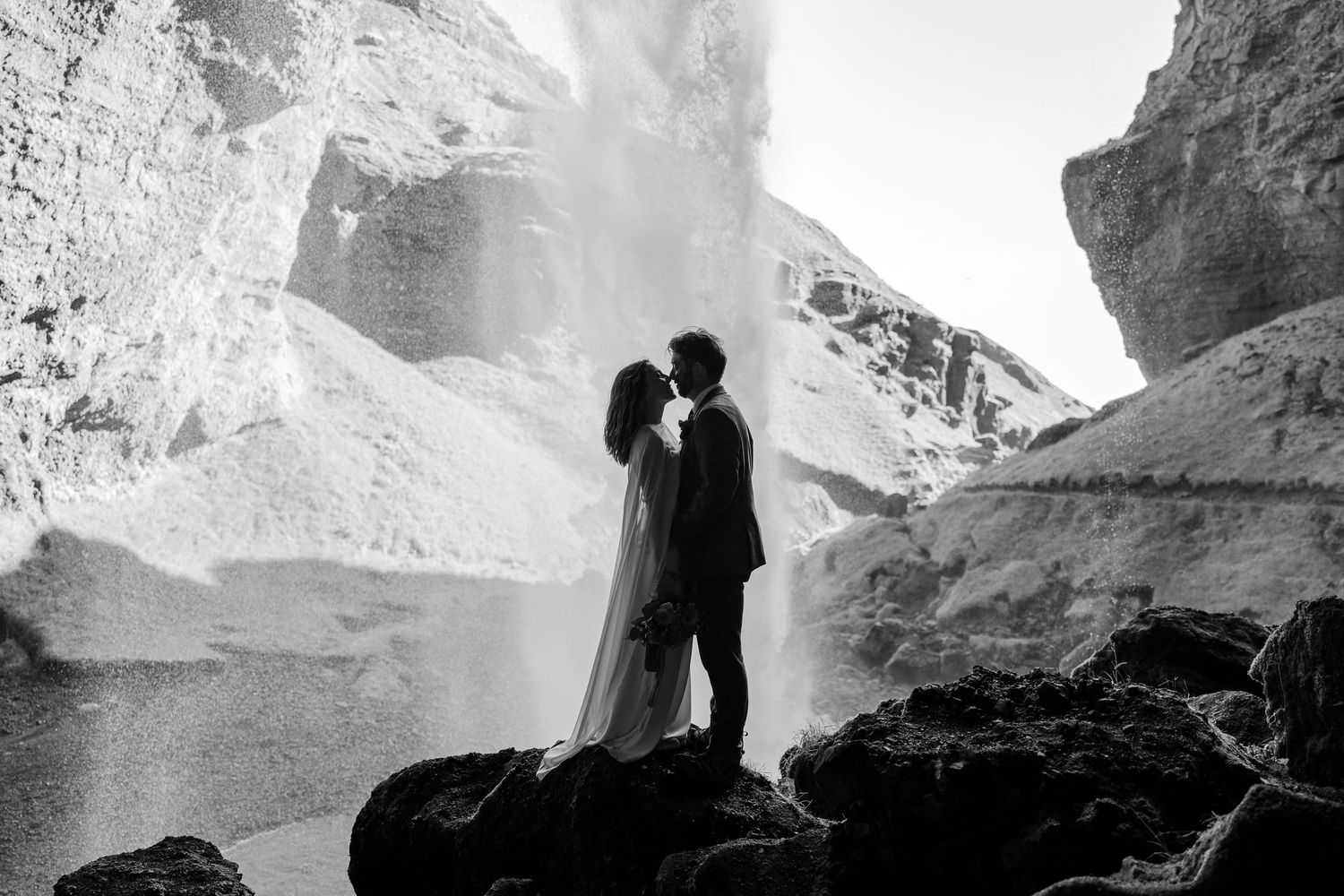 black and white photo of bride and groom about to kiss behind the Kvernufoss waterfall in Iceland during their elopement