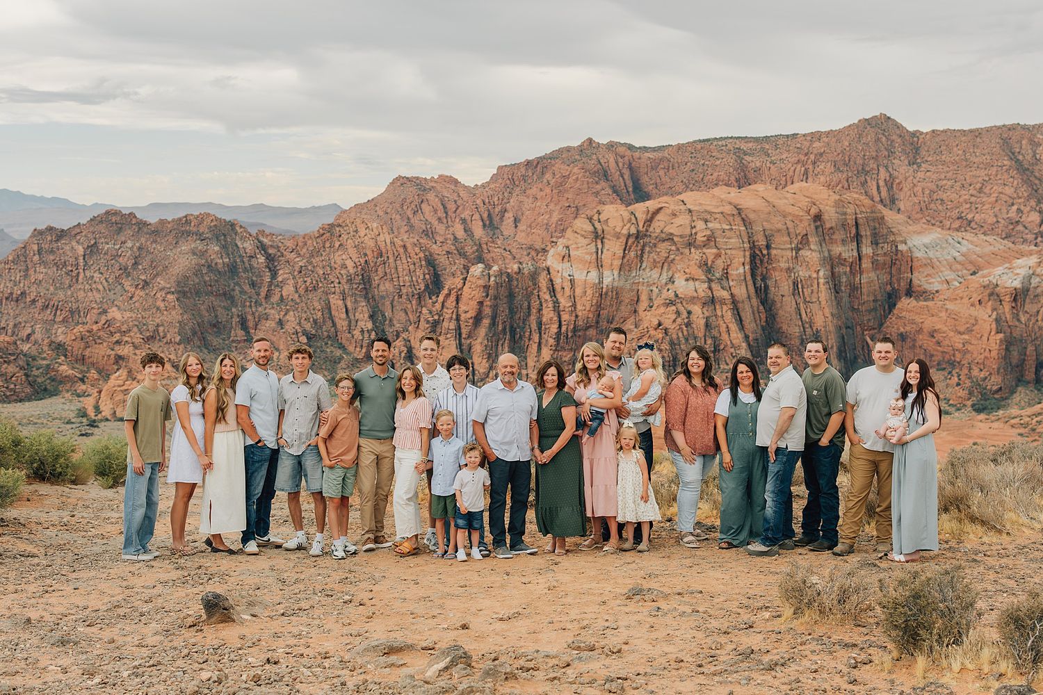 Large extended family group photo outdoors with stunning red rock canyon formations in the background.