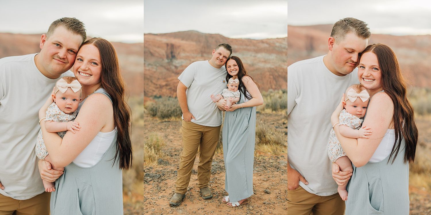 A couple poses with their newborn baby in a scenic desert landscape with red rock formations.
