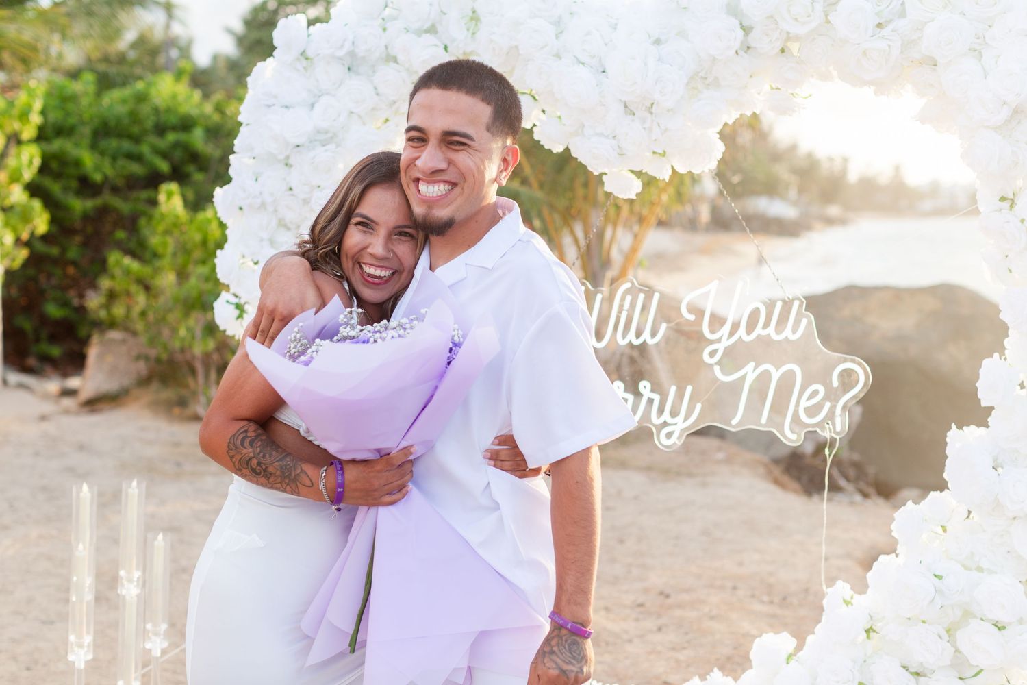 Marriage proposal. Man, woman, and decorative setup with white flower heart overlooking the ocean in Río Grande, Puerto Rico.