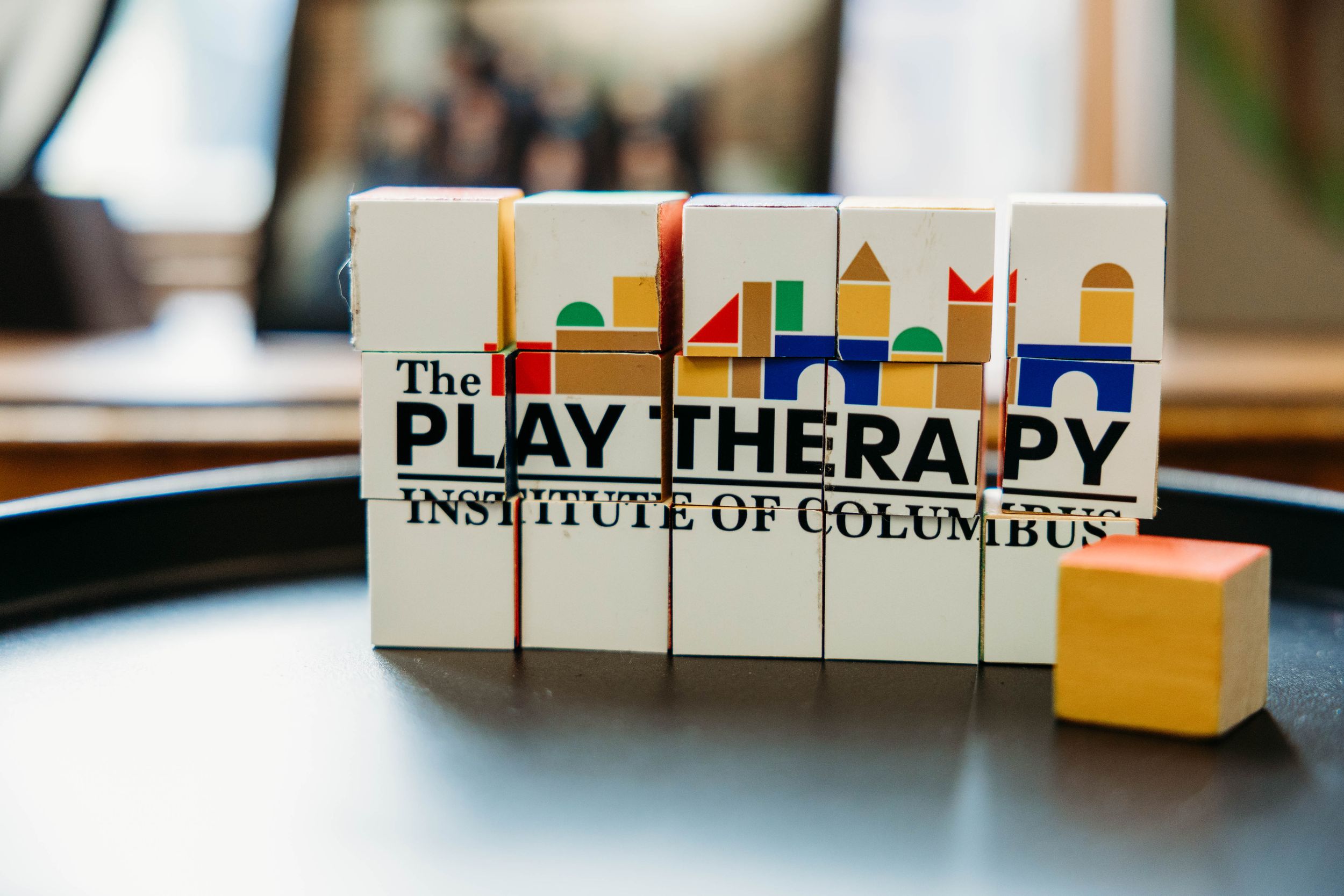 Colorful building blocks spelling Play Therapy Institute of Columbus logo on a table.