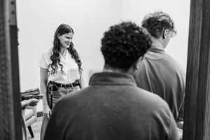 Black and white photo of three people in a room, woman smiling at two others.