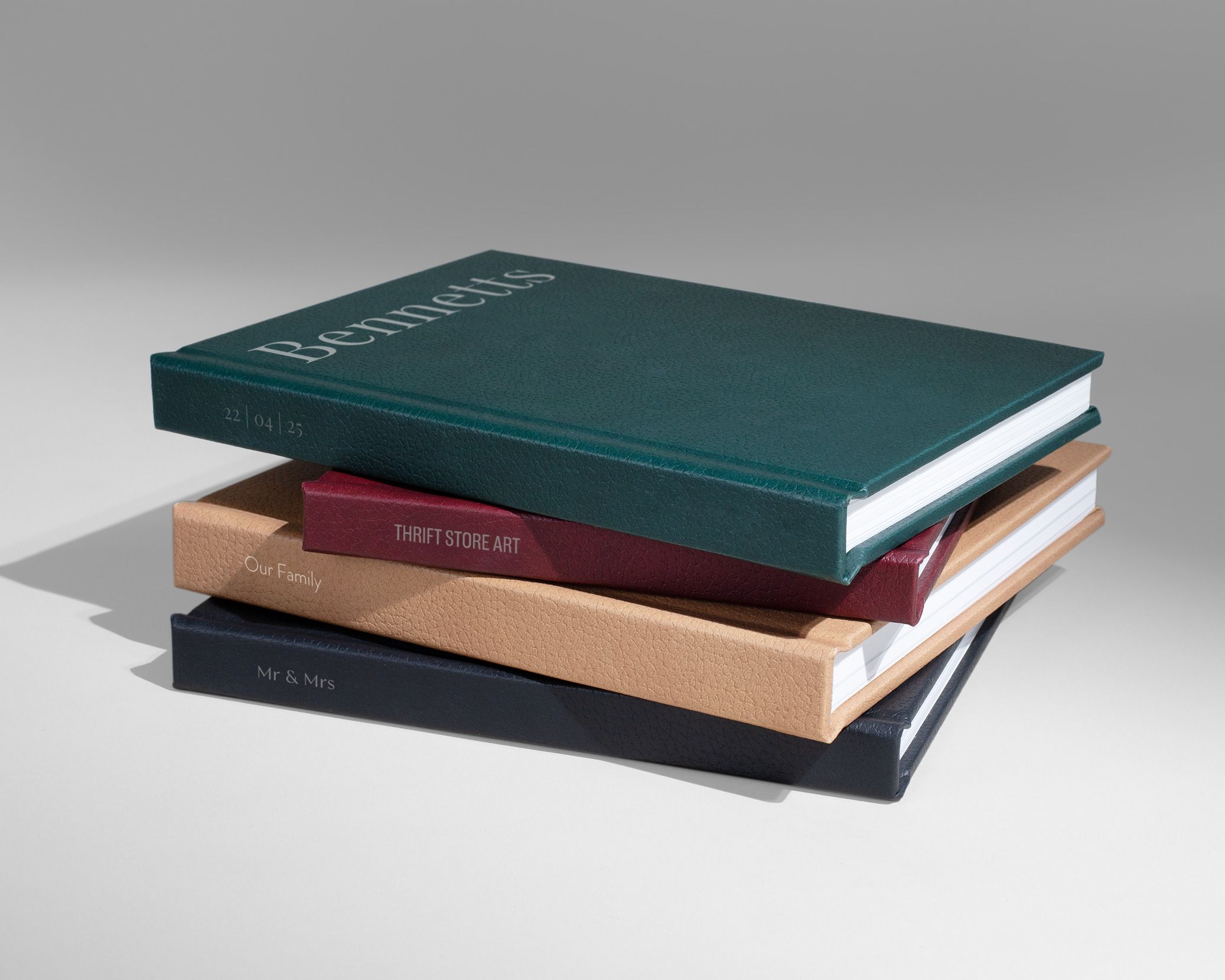 Stack of four hardcover books including Bennetts and Short Story Art on a neutral background.