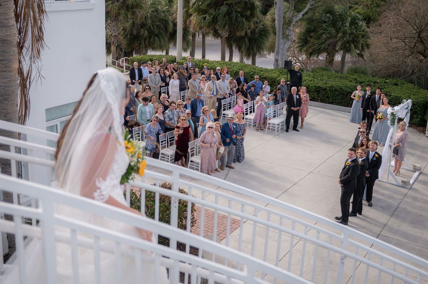 Bride on the curved staircase above her guests before walking down the aisle at the Mansion at Tuckahoe