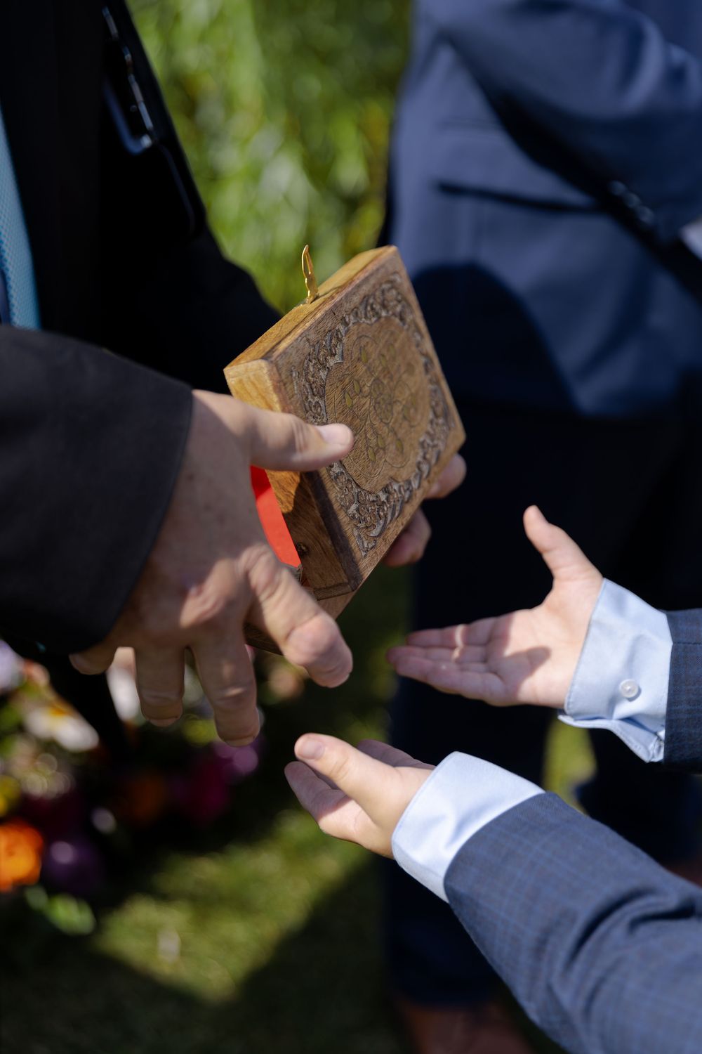Hands passing an ornate antique book with gold clasp during an outdoor wedding ceremony at barn swallow fields in guelph, ontario.