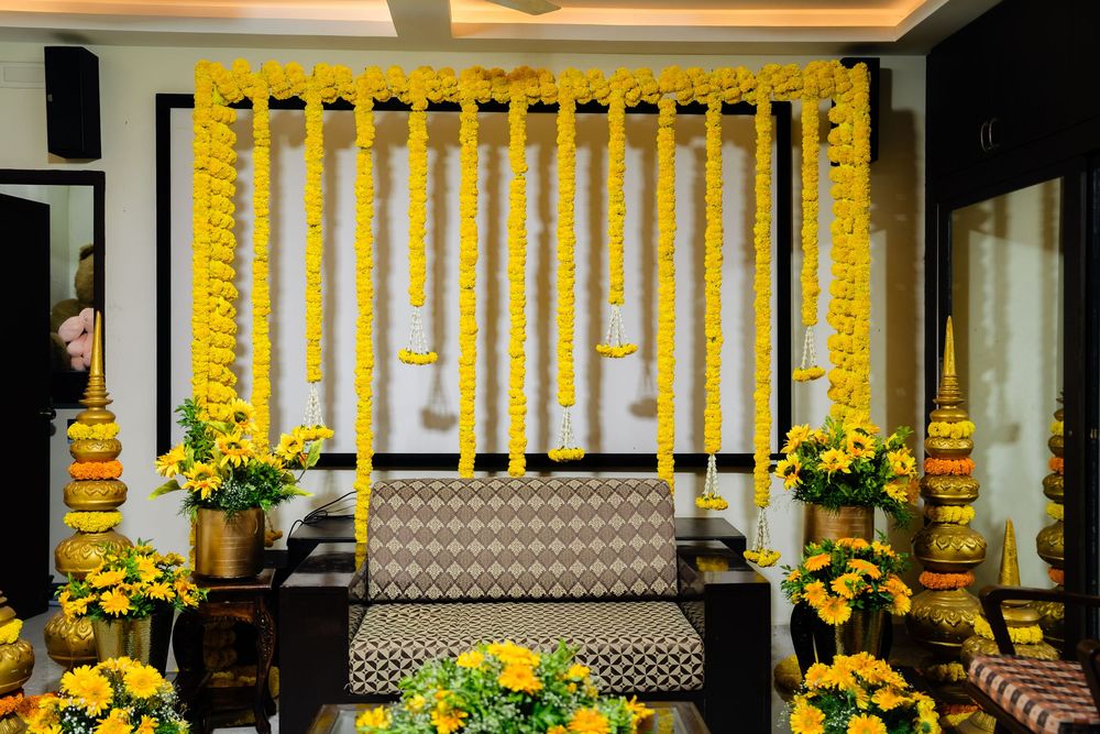 Vibrant Indian wedding mandap decorated with yellow marigold garlands and floral arrangements around a traditional sofa.