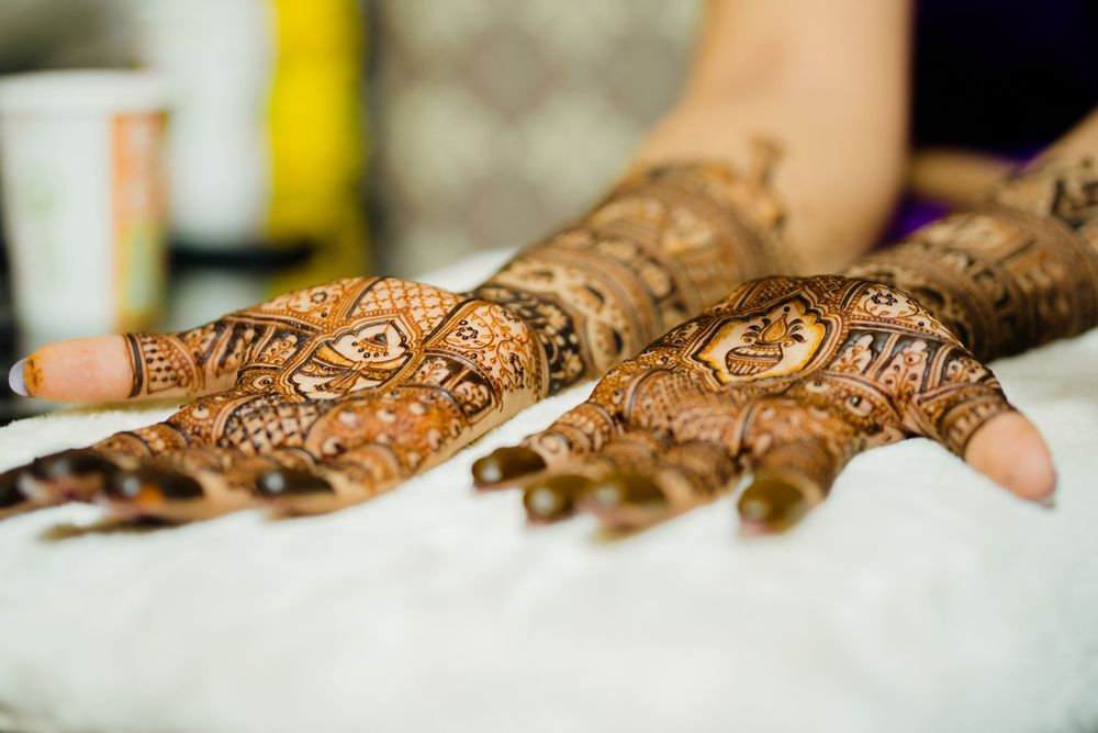 Close-up of intricate henna mehndi designs on both hands, showcasing traditional bridal body art patterns.