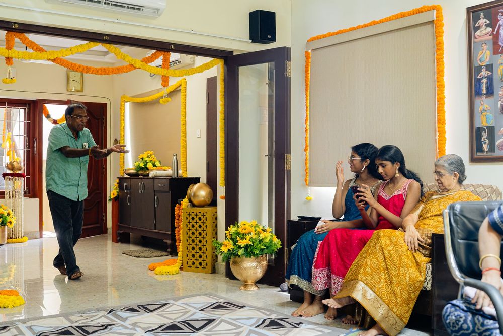 Indian family celebrating a festive occasion indoors, decorated with marigold flowers and traditional yellow ornaments.