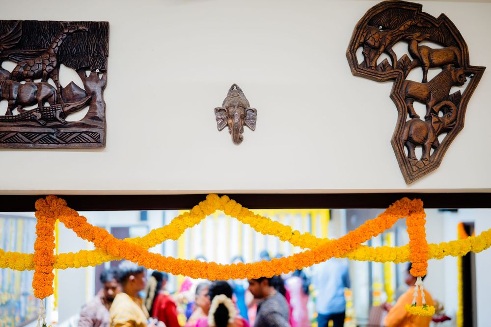 Decorative wooden wall art and Ganesha idol adorned with vibrant orange and yellow marigold garlands at an Indian celebration.