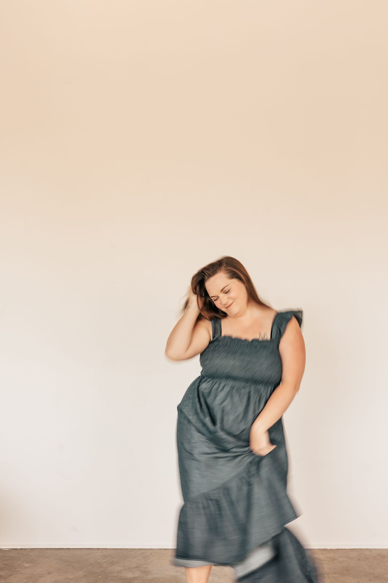 Woman in teal midi dress posing gracefully against a neutral background, with motion blur effect | Photography Business Coach