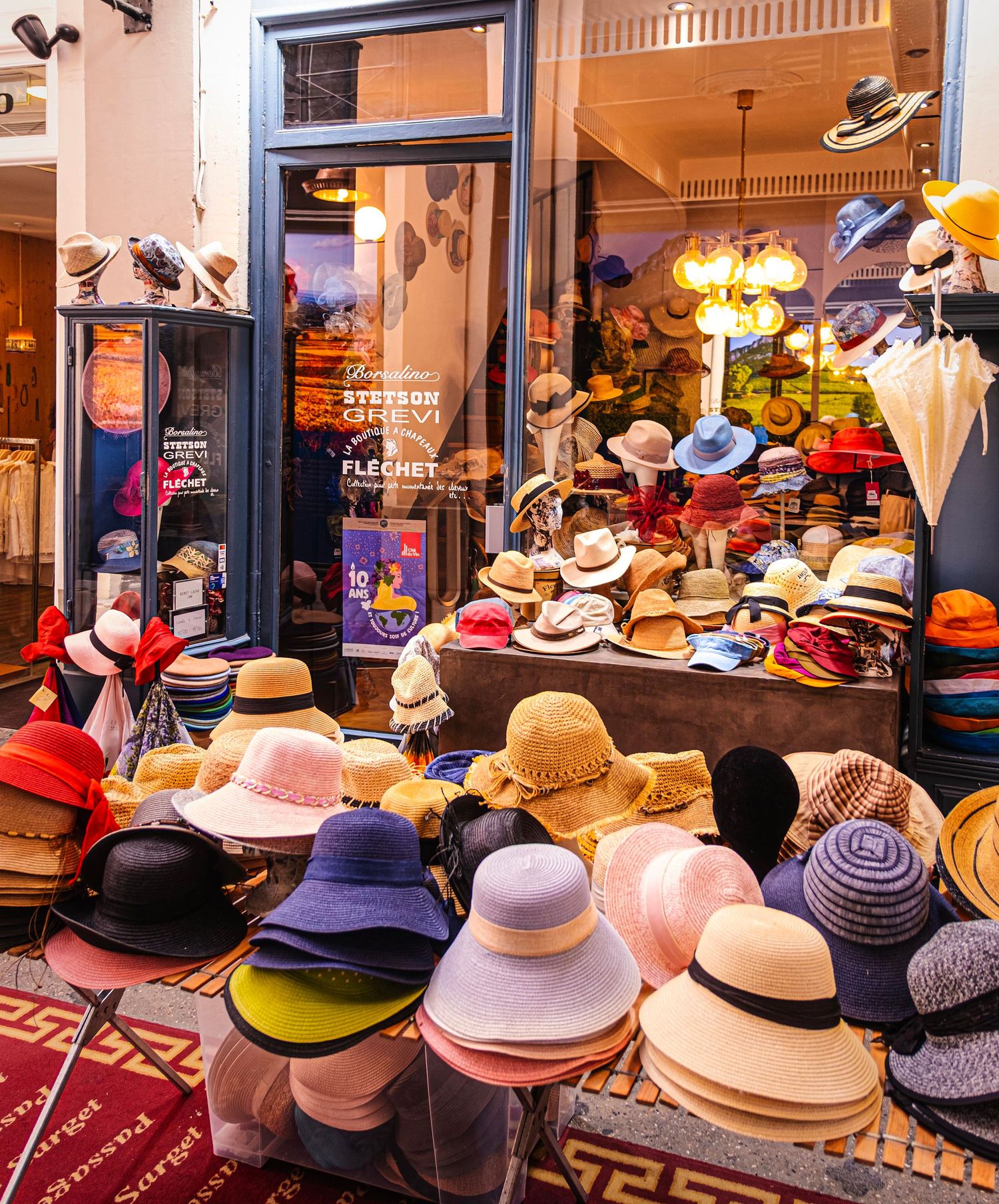 Colorful display of straw and fabric hats outside a hat shop storefront with Stetson and Flechet signage.