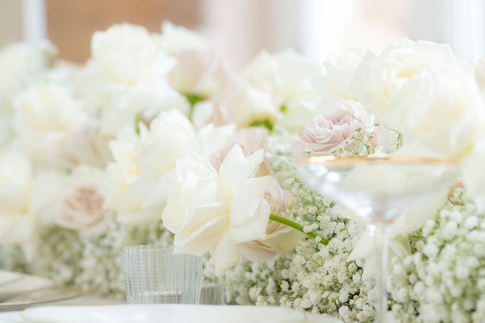 Delicate white floral arrangements with roses and baby's breath for wedding decor.