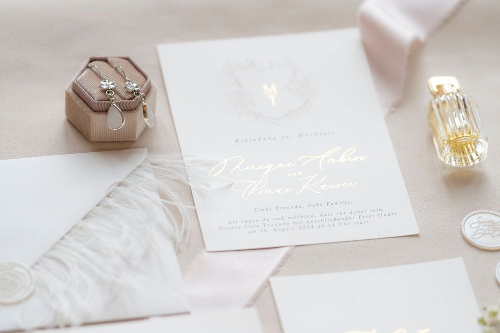 Elegant wedding stationery with gold accents and wax seals on marble surface.