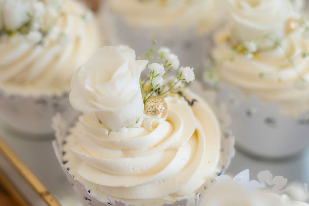 Close-up of elegant white frosted mini desserts topped with swirls of cream.