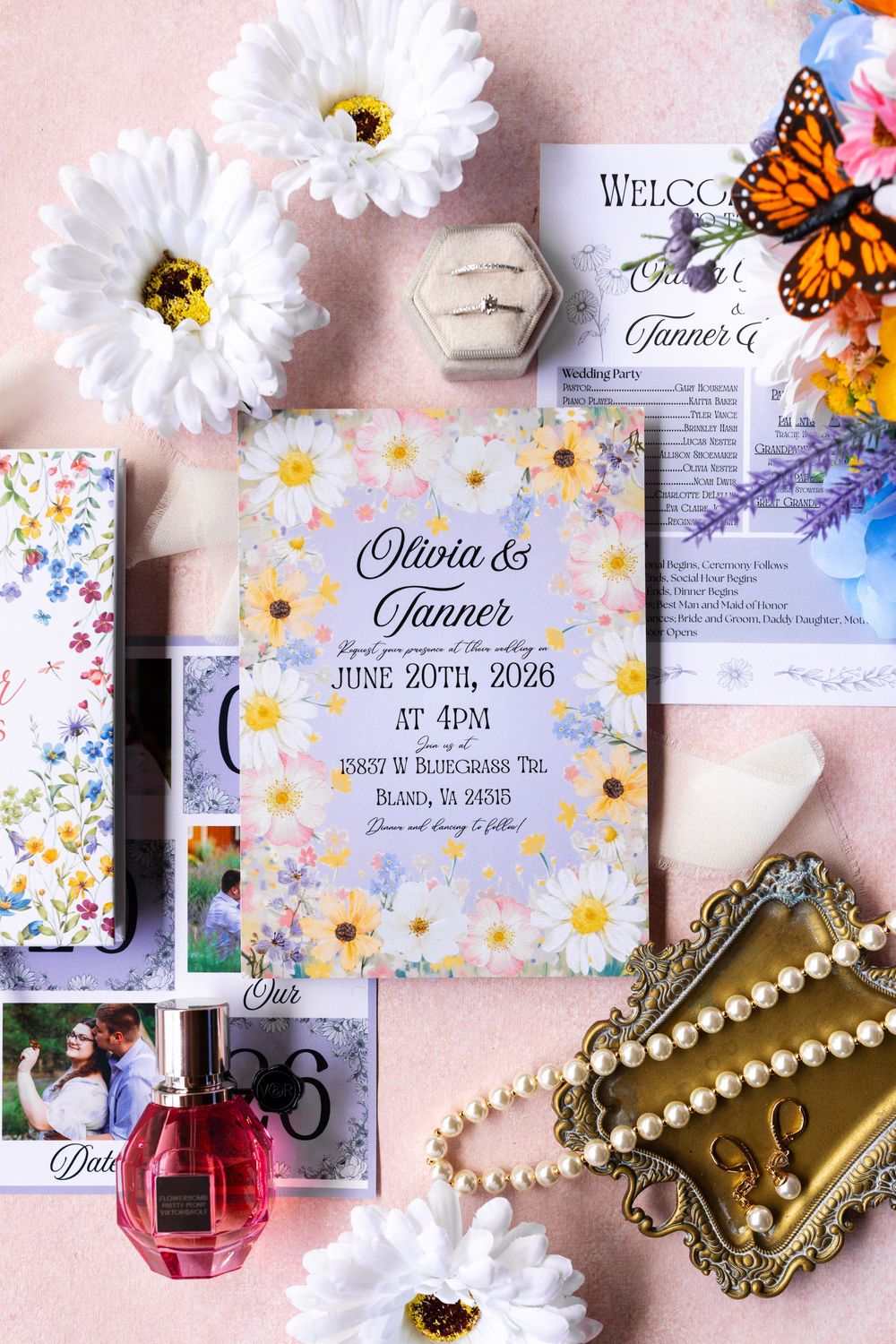 Floral wedding invitation for Olivia and Tanner, June 20th 2026, surrounded by daisies, pearls, perfume, and butterfly decor.
