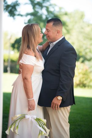 Bride and groom sharing a romantic moment outdoors, with the bride holding white calla lily bouquet.