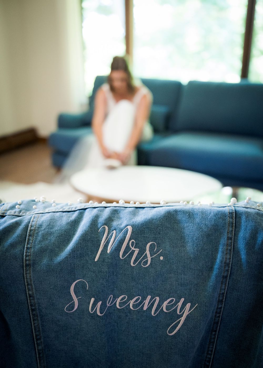 Custom denim jacket with Mrs. Sweeney written on the back, with bride sitting in background.
