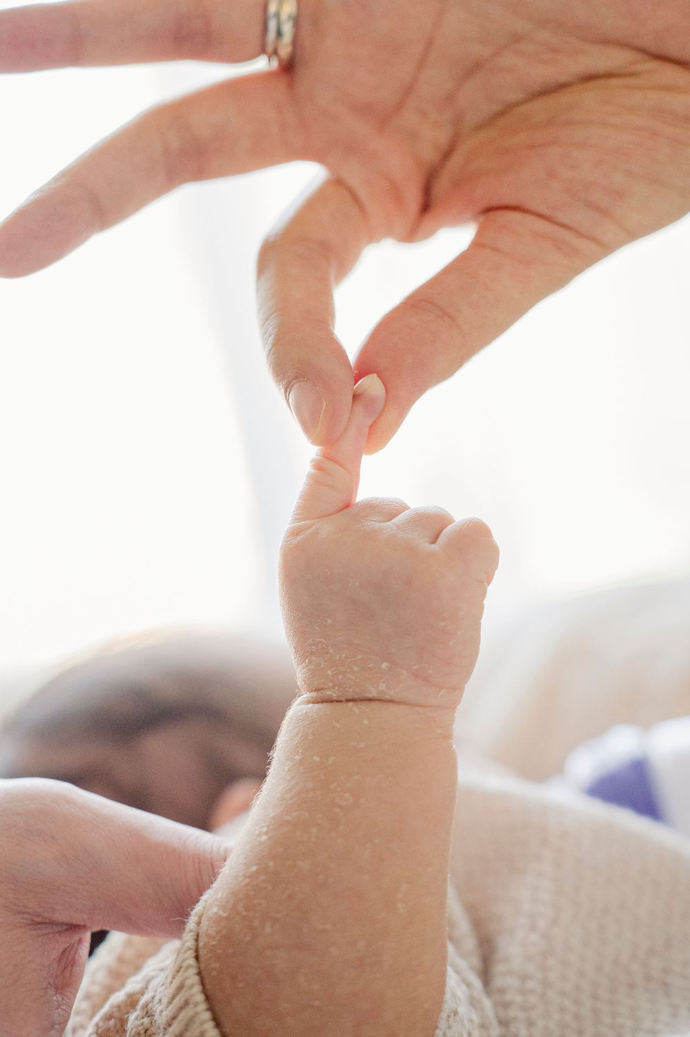 Close-up of a baby's tiny hand grasping an adult's finger, symbolizing love and new life.