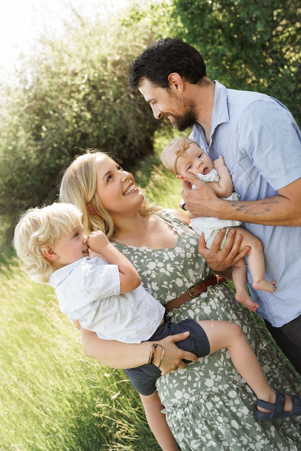 Happy family with two young children enjoying a sunny day outdoors in a green park setting.