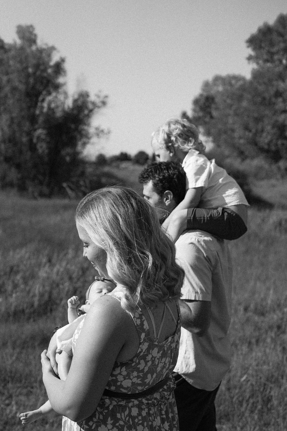 Black and white family photo of parents holding two young children in a grassy field.