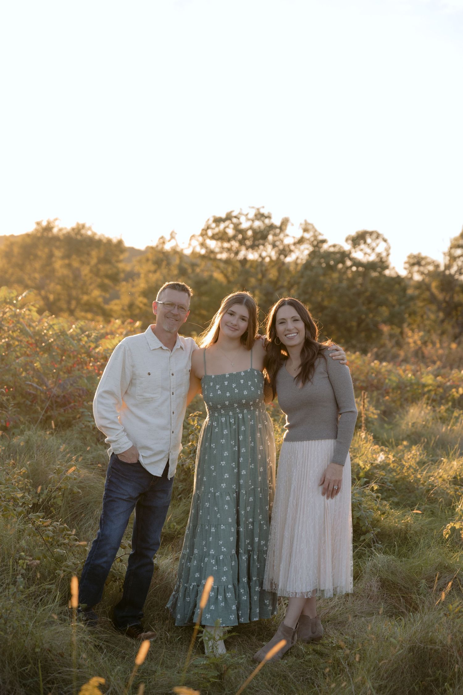 the sun falling over parents and their teenage daughter during a fall family portrait session in hudson wisconsin
