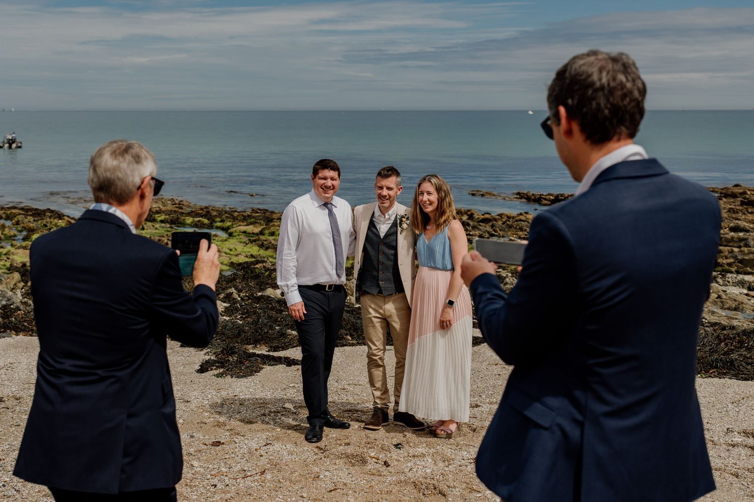 Cornwall wedding photographer captures candid moment of guests laughing during portraits on the beach at Hotel Meudon