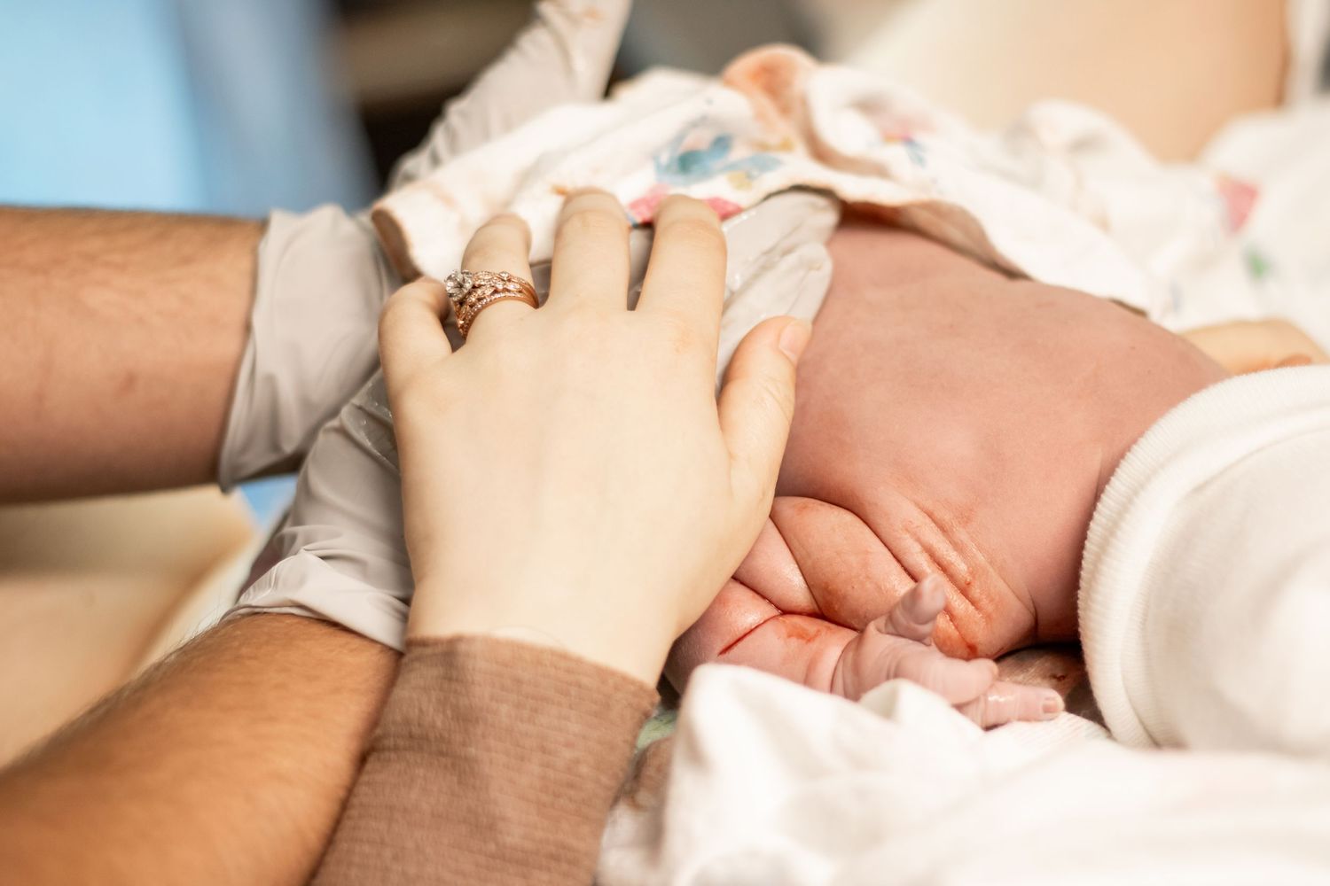 Newborn baby grasping parents fingers moments after birth in hospital.