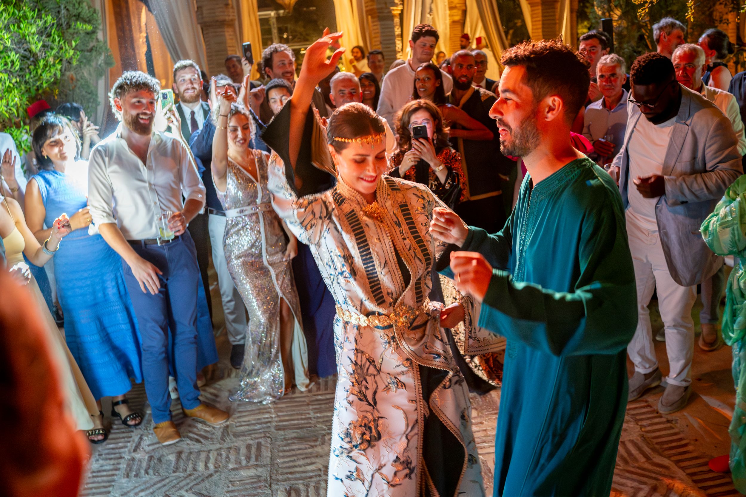 Couple dancing at a vibrant Moroccan-themed wedding celebration with guests watching.