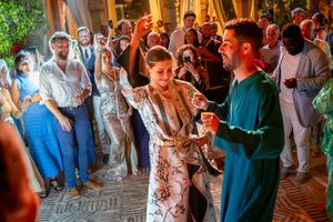 Couple dancing at a vibrant Moroccan-themed wedding celebration with guests watching.