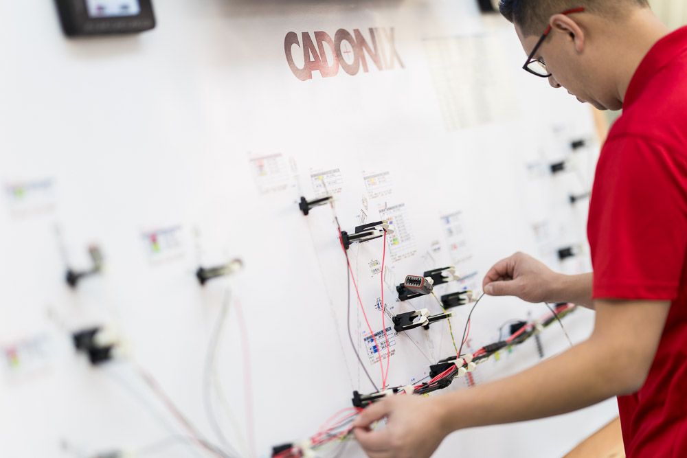Engineer wiring an electrical loom using specialist design equipment in a manufacturing environment.