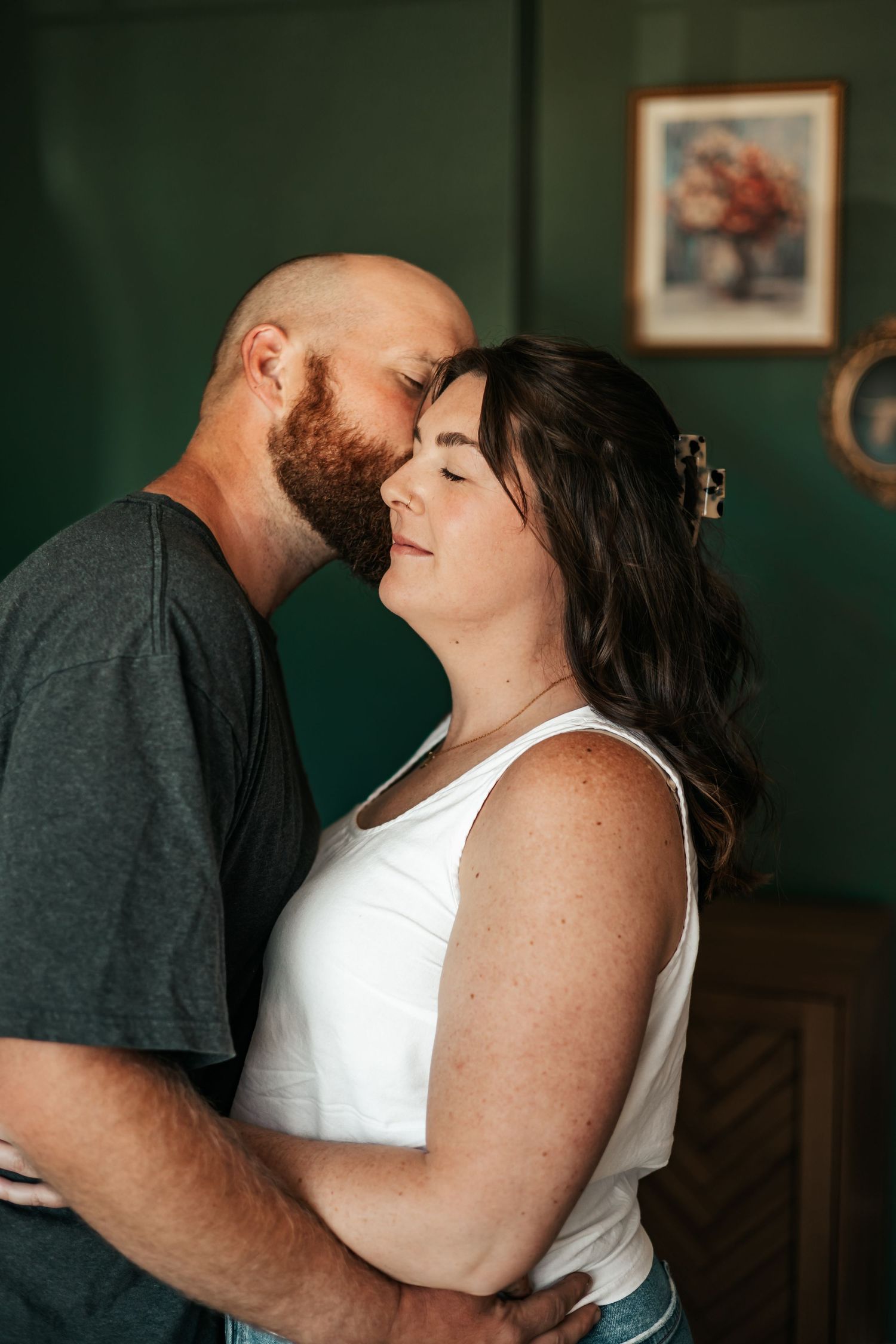 A bald bearded man tenderly kisses a dark-haired woman on the forehead  | Anniversary Photos in Johnston, Colorado